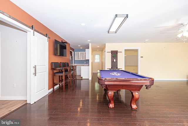 recreation room featuring ceiling fan, billiards, a barn door, and dark hardwood / wood-style flooring