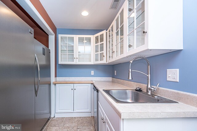 kitchen featuring stainless steel appliances, sink, and white cabinetry