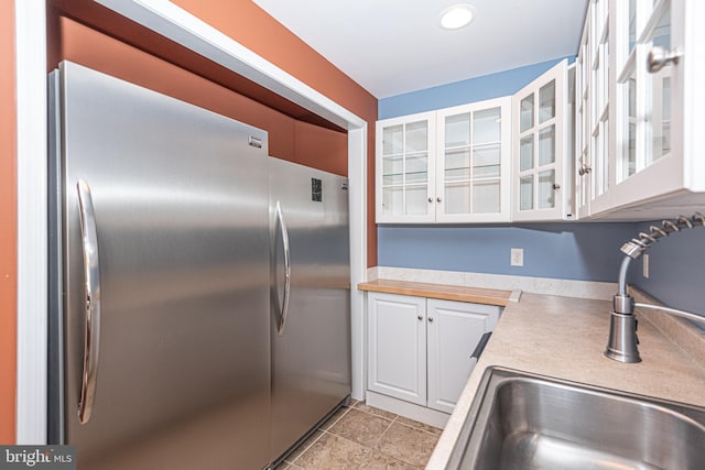 kitchen with white cabinets, sink, and stainless steel refrigerator