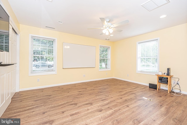 spare room with light wood-type flooring, ceiling fan, and a healthy amount of sunlight