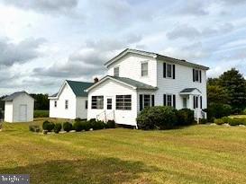 view of front of property featuring a storage shed and a front yard