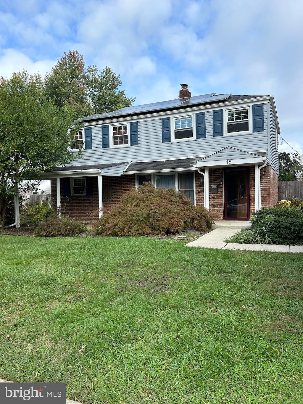 front facade featuring solar panels and a front lawn