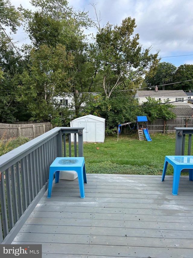 wooden deck featuring a storage shed, a playground, and a yard