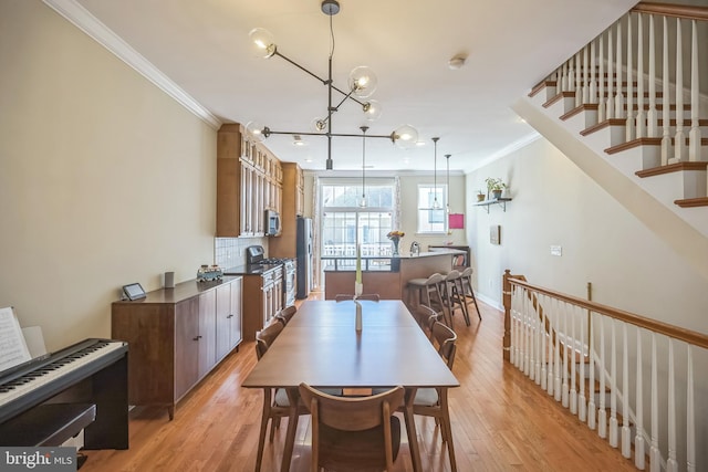 dining area featuring an inviting chandelier, light hardwood / wood-style flooring, and ornamental molding