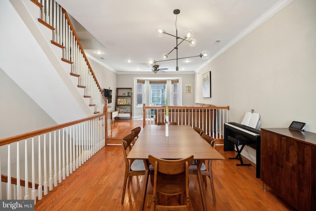 dining area featuring ceiling fan with notable chandelier, light hardwood / wood-style flooring, and ornamental molding