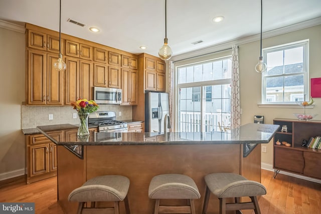 kitchen featuring decorative backsplash, stainless steel appliances, light hardwood / wood-style floors, crown molding, and decorative light fixtures