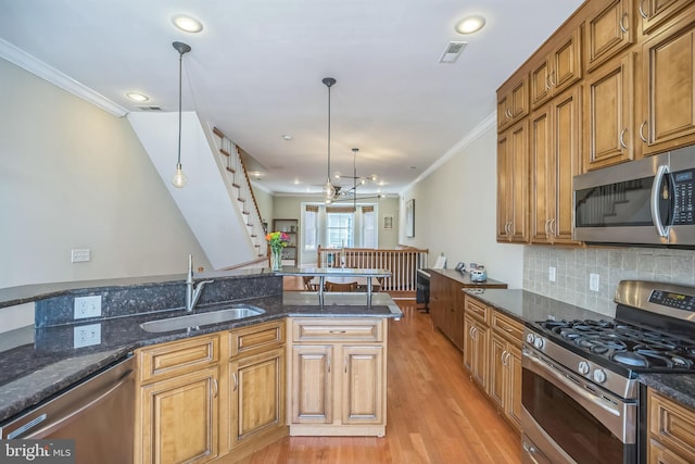 kitchen featuring pendant lighting, stainless steel appliances, sink, and light hardwood / wood-style flooring