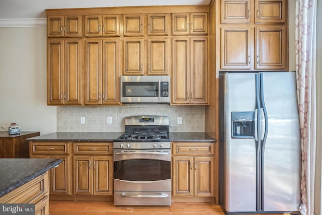 kitchen featuring ornamental molding, dark stone counters, stainless steel appliances, light wood-type flooring, and decorative backsplash