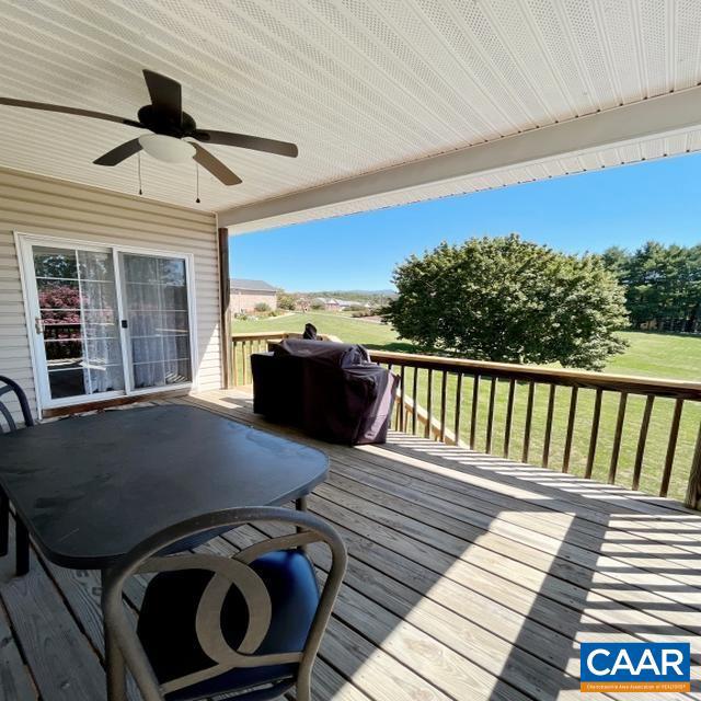 wooden terrace featuring ceiling fan, a grill, and a lawn