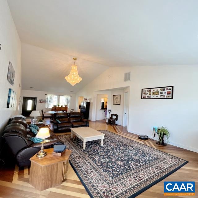 living room featuring lofted ceiling, a chandelier, and light hardwood / wood-style flooring