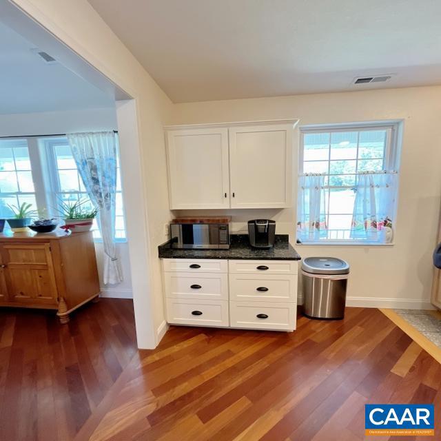 interior space with dark stone countertops, dark hardwood / wood-style flooring, and white cabinetry