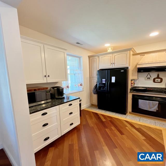 kitchen featuring white cabinets, black appliances, dark hardwood / wood-style floors, and premium range hood