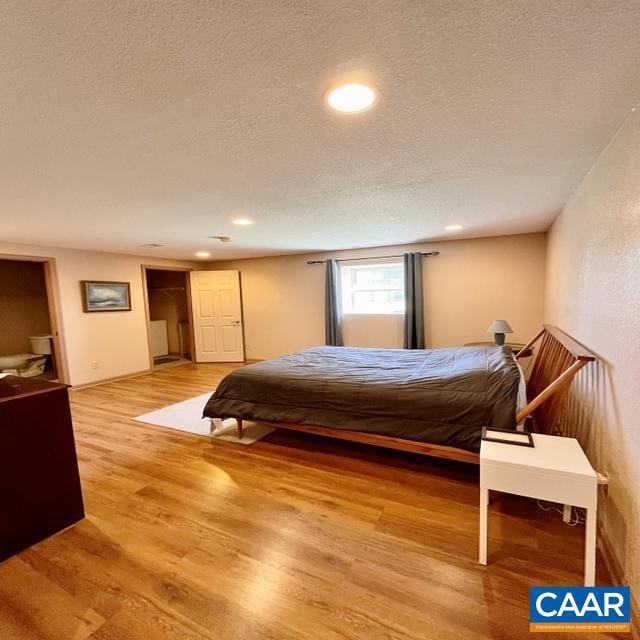 bedroom with a textured ceiling and wood-type flooring