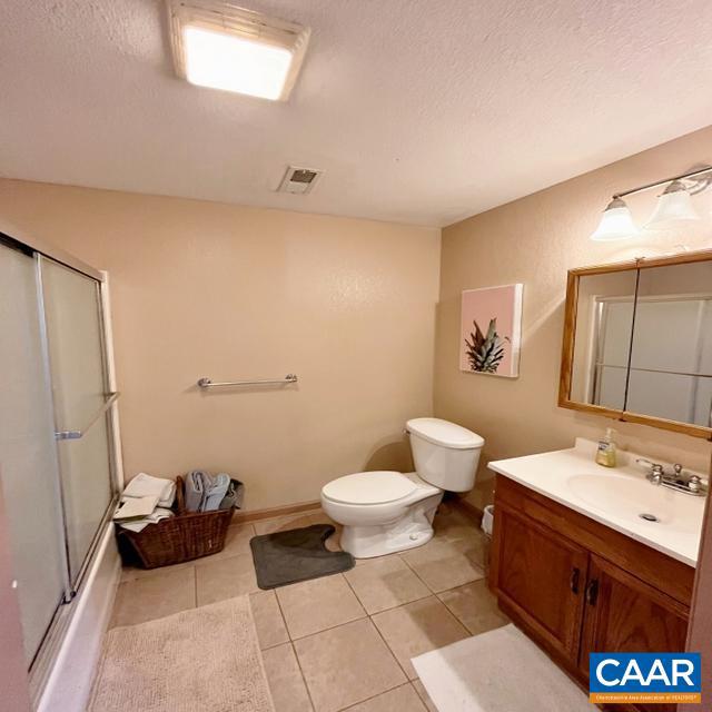 bathroom with a textured ceiling, tile patterned flooring, vanity, and toilet