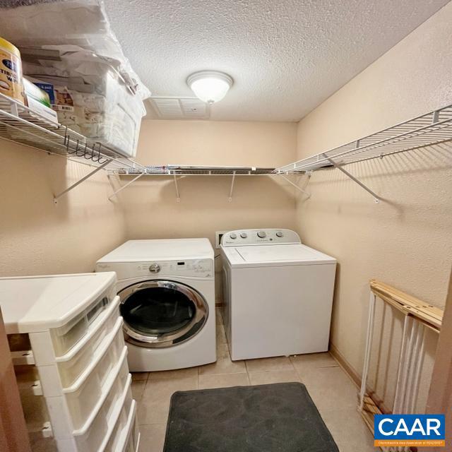 clothes washing area with light tile patterned floors, a textured ceiling, and separate washer and dryer