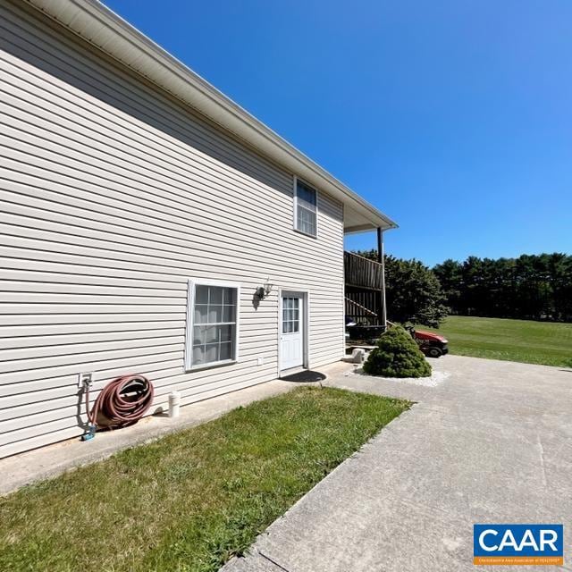 view of side of home with a patio area and a yard