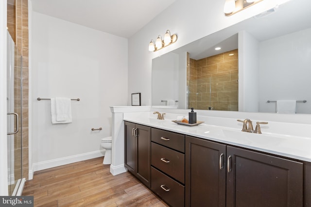 bathroom featuring vanity, toilet, wood-type flooring, and a shower with door