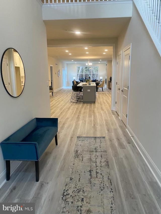 hallway featuring an inviting chandelier and light hardwood / wood-style floors