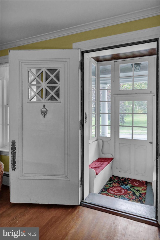 doorway featuring vaulted ceiling, hardwood / wood-style floors, and crown molding