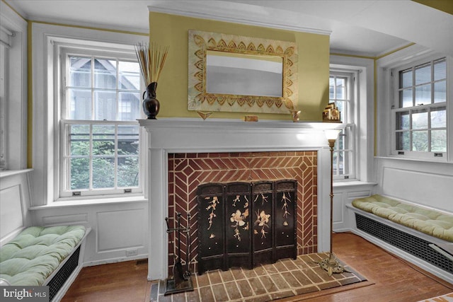 interior details with crown molding, a fireplace, radiator, and hardwood / wood-style floors