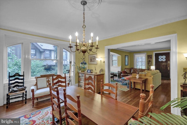 dining area with wood-type flooring, a chandelier, a healthy amount of sunlight, and crown molding