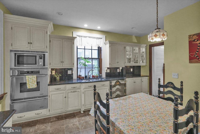 kitchen featuring stainless steel appliances, decorative light fixtures, tasteful backsplash, and sink