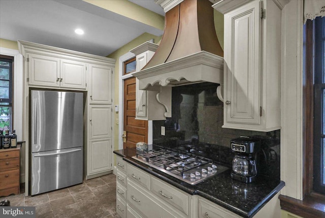 kitchen featuring decorative backsplash, stainless steel appliances, white cabinets, and premium range hood