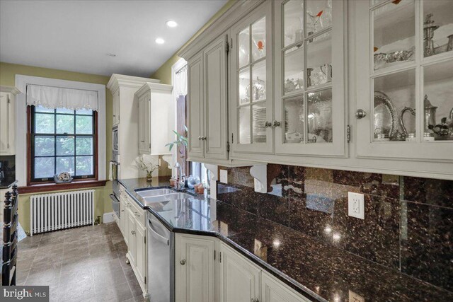 bar with white cabinetry, backsplash, dishwasher, radiator, and dark stone counters