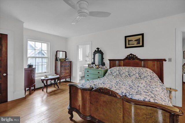 bedroom with light hardwood / wood-style flooring, radiator, ensuite bath, and ceiling fan