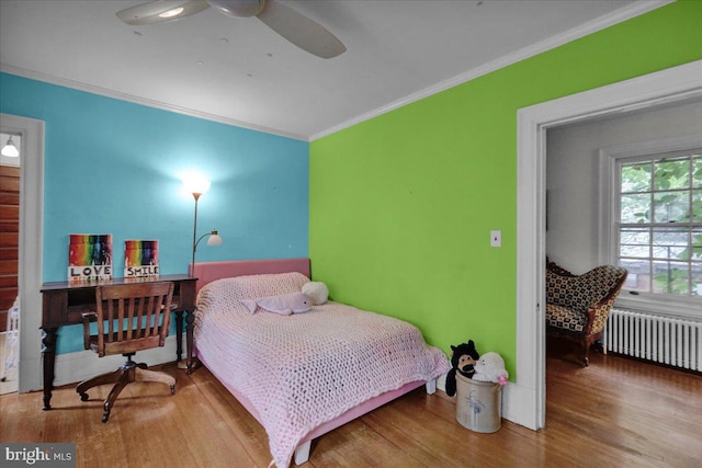 bedroom featuring wood-type flooring, ornamental molding, ceiling fan, and radiator heating unit