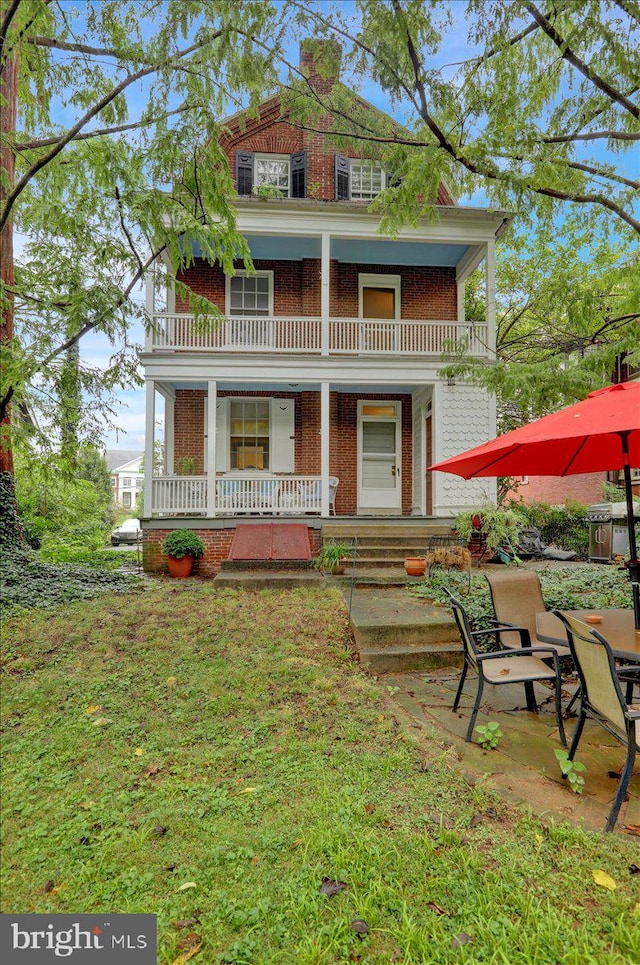 neoclassical home with a front yard, a balcony, and a porch