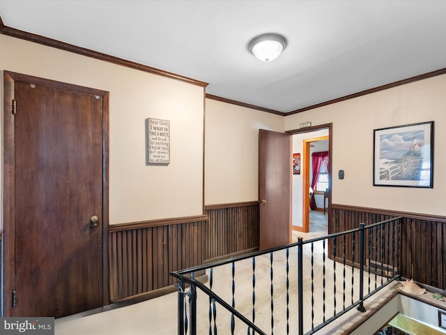 hall with light colored carpet, crown molding, and wood walls