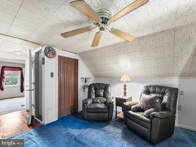 sitting room featuring dark carpet, vaulted ceiling, and ceiling fan