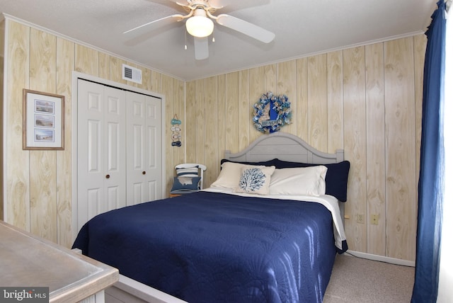 bedroom featuring wooden walls, ceiling fan, a closet, and carpet flooring