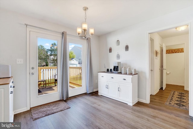 doorway with a chandelier and light hardwood / wood-style floors