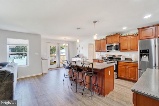 kitchen with light wood-type flooring, a kitchen breakfast bar, decorative light fixtures, stainless steel appliances, and a center island