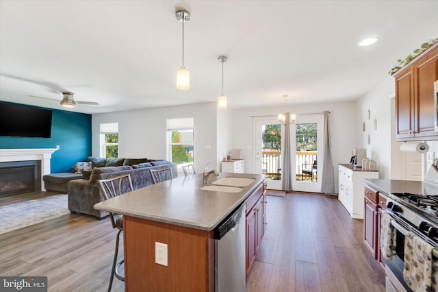 kitchen with a kitchen island with sink, dark hardwood / wood-style floors, sink, appliances with stainless steel finishes, and decorative light fixtures