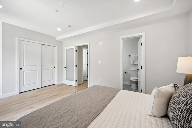 bedroom with connected bathroom, a closet, and light wood-type flooring