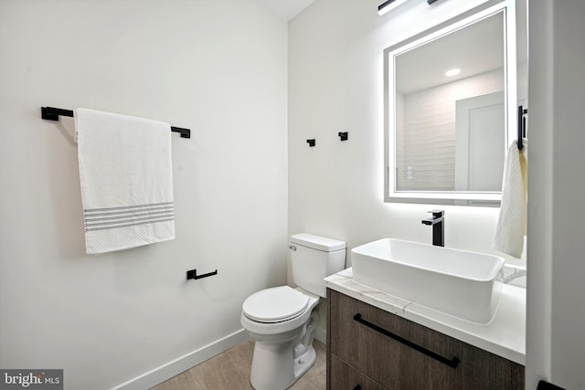 bathroom with vanity, toilet, and hardwood / wood-style flooring