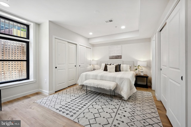 bedroom featuring light hardwood / wood-style flooring and two closets