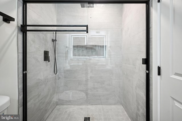 bathroom featuring a shower with shower door and toilet