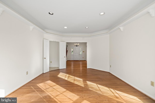 spare room with crown molding, an inviting chandelier, and hardwood / wood-style flooring