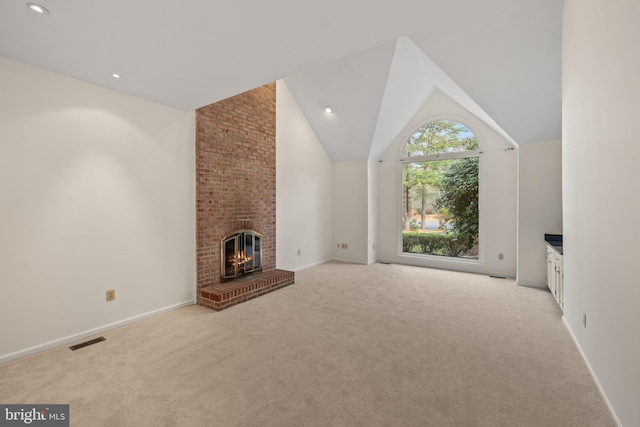 unfurnished living room featuring light carpet, high vaulted ceiling, and a brick fireplace