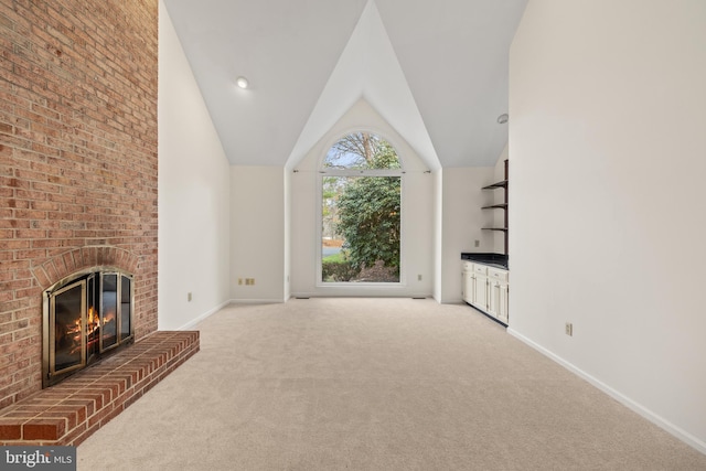 unfurnished living room featuring carpet flooring, vaulted ceiling, and a brick fireplace