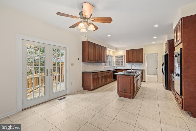 kitchen with tasteful backsplash, a kitchen island with sink, a healthy amount of sunlight, and ceiling fan