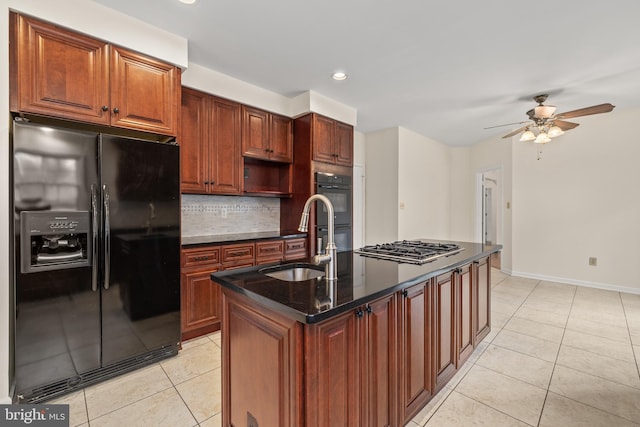 kitchen featuring backsplash, a kitchen island with sink, sink, black appliances, and light tile patterned floors