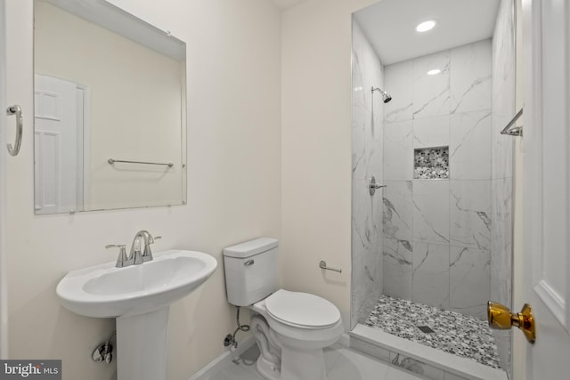 bathroom with tiled shower, toilet, and sink