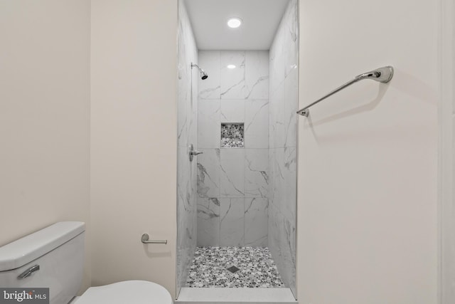 bathroom with a tile shower and toilet