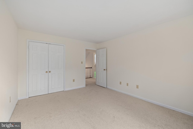 unfurnished bedroom featuring light carpet and a closet