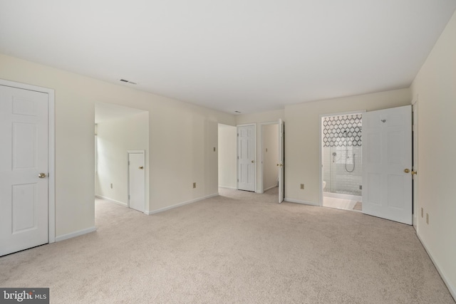 unfurnished bedroom featuring light colored carpet and connected bathroom